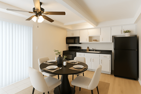 San Leandro apartment for rent - A black refrigerator sits in a kitchen with white cabinets and a table set for two.