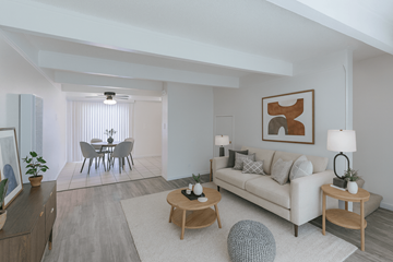 San Leandro apartment for rent - A living room with a white couch, a dining table with chairs, and a ceiling fan.