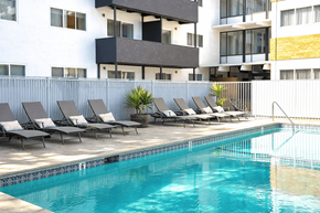 San Leandro apartment for rent - A pool with lounge chairs in front of a building.