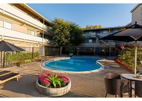Walnut Creek apartment for rent - A pool surrounded by chairs and umbrellas in a courtyard.