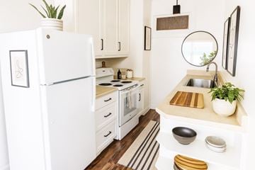Alameda apartment for rent - A white refrigerator stands in a kitchen with a sink and a mirror.