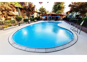 Fremont apartment for rent - A blue swimming pool surrounded by a fence and trees.