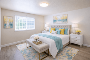 San Leandro apartment for rent - A bedroom with a white bed and a blue and yellow throw blanket.