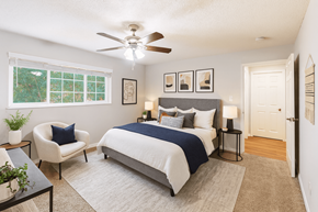 Newark apartment for rent - A bedroom with a bed, chair, and a ceiling fan.