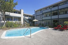 San Jose apartment for rent - A swimming pool with red chairs and a white umbrella.