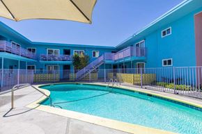 San Jose apartment for rent - A blue building with a pool in front.