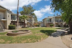 Fairfield apartment for rent - A sunny day in a residential area with apartment buildings and a small fountain in the middle of a grassy area.