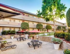San Leandro apartment for rent - A courtyard with tables and chairs is surrounded by a building.