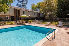 Concord apartment for rent - A swimming pool in a backyard with a fence and chairs.
