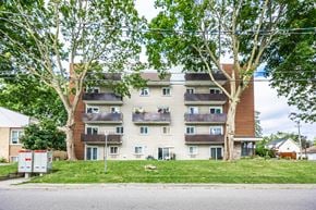 Whitby apartment for rent - A large apartment building with multiple balconies and trees in front.