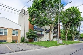 Whitby apartment for rent - A street view of a residential area with apartment buildings and trees.