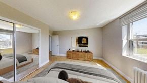 North York apartment for rent - A bedroom with a large bed and a wooden bench in the middle of the room.