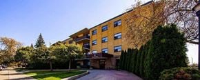 North York apartment for rent - A large building with a yellow facade is surrounded by greenery.