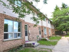 London townhouse for rent - A brick house with a white door and a window with white curtains.