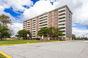 Mississauga apartment for rent - A large apartment building with a parking lot in front.