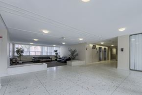 Mississauga apartment for rent - A spacious room with white tiled flooring and a large window.