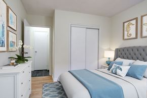 Brampton apartment for rent - A bedroom with a bed, nightstand, and a dresser with a plant on top.