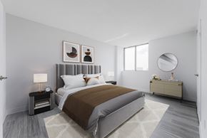 Mississauga apartment for rent - A bedroom with a large bed and a nightstand with a lamp.