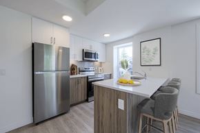 Waterloo apartment for rent - A kitchen with a stainless steel refrigerator, wooden countertops, and grey barstools.