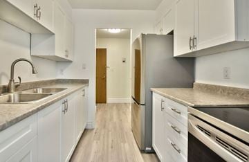 Barrie apartment for rent - A kitchen with white cabinets and a wooden floor.