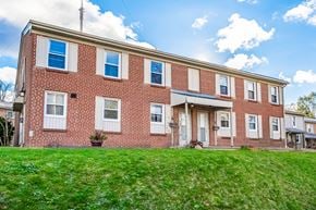London townhouse for rent - A red brick building with white trim and a green lawn in front.