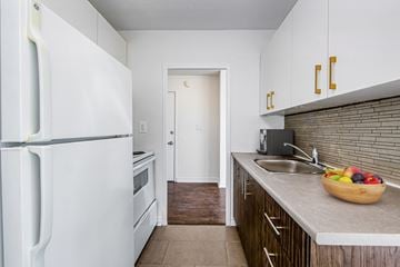 Toronto apartment for rent - A kitchen with a white fridge, wooden cabinets and a bowl of fruit on the counter.