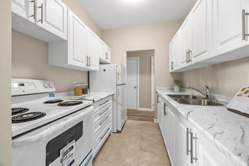 Whitby apartment for rent - A kitchen with white cabinets and a white stove top oven.