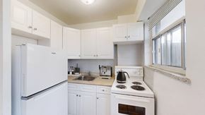 Toronto apartment for rent - A white kitchen with a stove, sink, and cabinets.