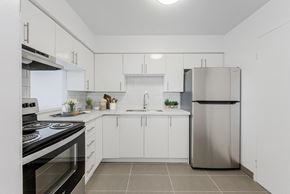 Mississauga apartment for rent - A modern kitchen with white cabinets and a stainless steel refrigerator.