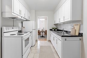 London apartment for rent - A white kitchen with a black counter top and a tile floor.