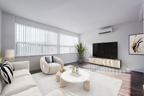 Toronto apartment for rent - A modern living room with a white sofa, a white armchair, a white coffee table, and a flat screen TV.