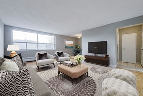 North York apartment for rent - A living room with a grey sofa, a brown coffee table, and a television.