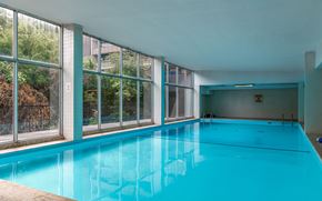 Toronto apartment for rent - A large indoor swimming pool with a view of trees outside.