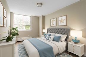 Scarborough apartment for rent - A bedroom with a large bed, a blue blanket, and a white nightstand with a blue lamp.
