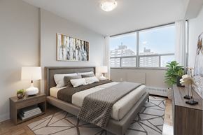 North York apartment for rent - A bedroom with a large bed and a view of the city.