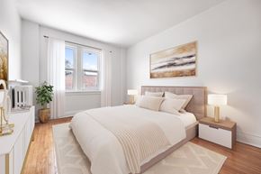Toronto apartment for rent - A bedroom with a large bed, a nightstand with a lamp, and a painting on the wall.