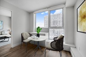Toronto apartment for rent - A dining room with a table and chairs and a view of a building outside the window.