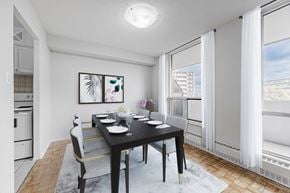 North York apartment for rent - A dining room with a table set for two and a view of a building outside the window.