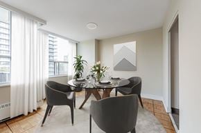 Toronto apartment for rent - A dining room with a table set for two and a view of a building outside the window.