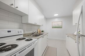 Toronto apartment for rent - A white kitchen with a stove, sink, and refrigerator.