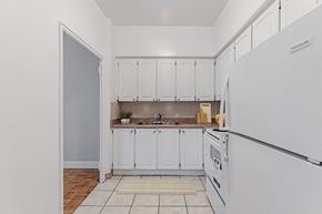 North York apartment for rent - A kitchen with white cabinets and a white fridge.
