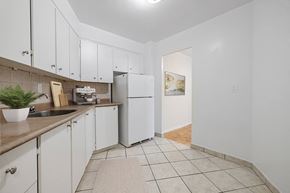North York apartment for rent - A kitchen with white cabinets and a white fridge.