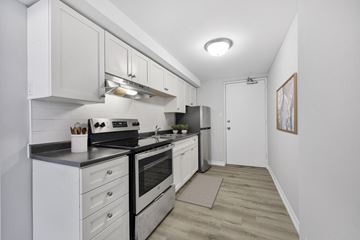 North York apartment for rent - A kitchen with white cabinets and a stove top oven.