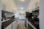 Toronto apartment for rent - A modern kitchen with white cabinets and a black stove top.