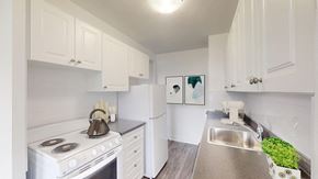 Toronto apartment for rent - A white kitchen with a stove, sink, and cabinets.