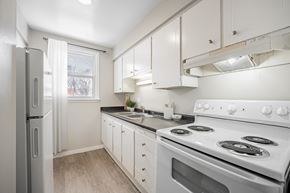 London townhouse for rent - A white kitchen with a stove, sink, and refrigerator.