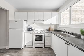 London townhouse for rent - A white kitchen with a refrigerator, oven, and sink.