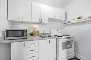Toronto apartment for rent - A white kitchen with a microwave, sink, and stove.