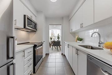 Toronto apartment for rent - A modern kitchen with white cabinets and stainless steel appliances.