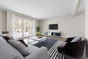 London townhouse for rent - A living room with a grey couch, a black chair, and a television.
